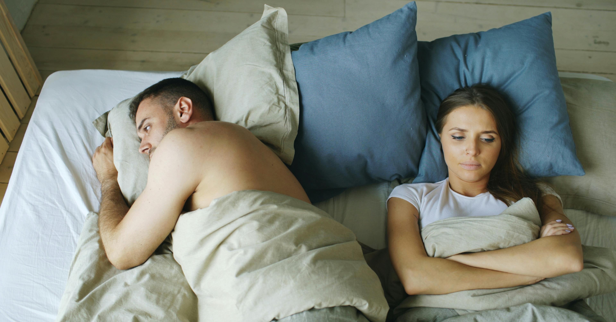 Couple sleeping in the same bed awake